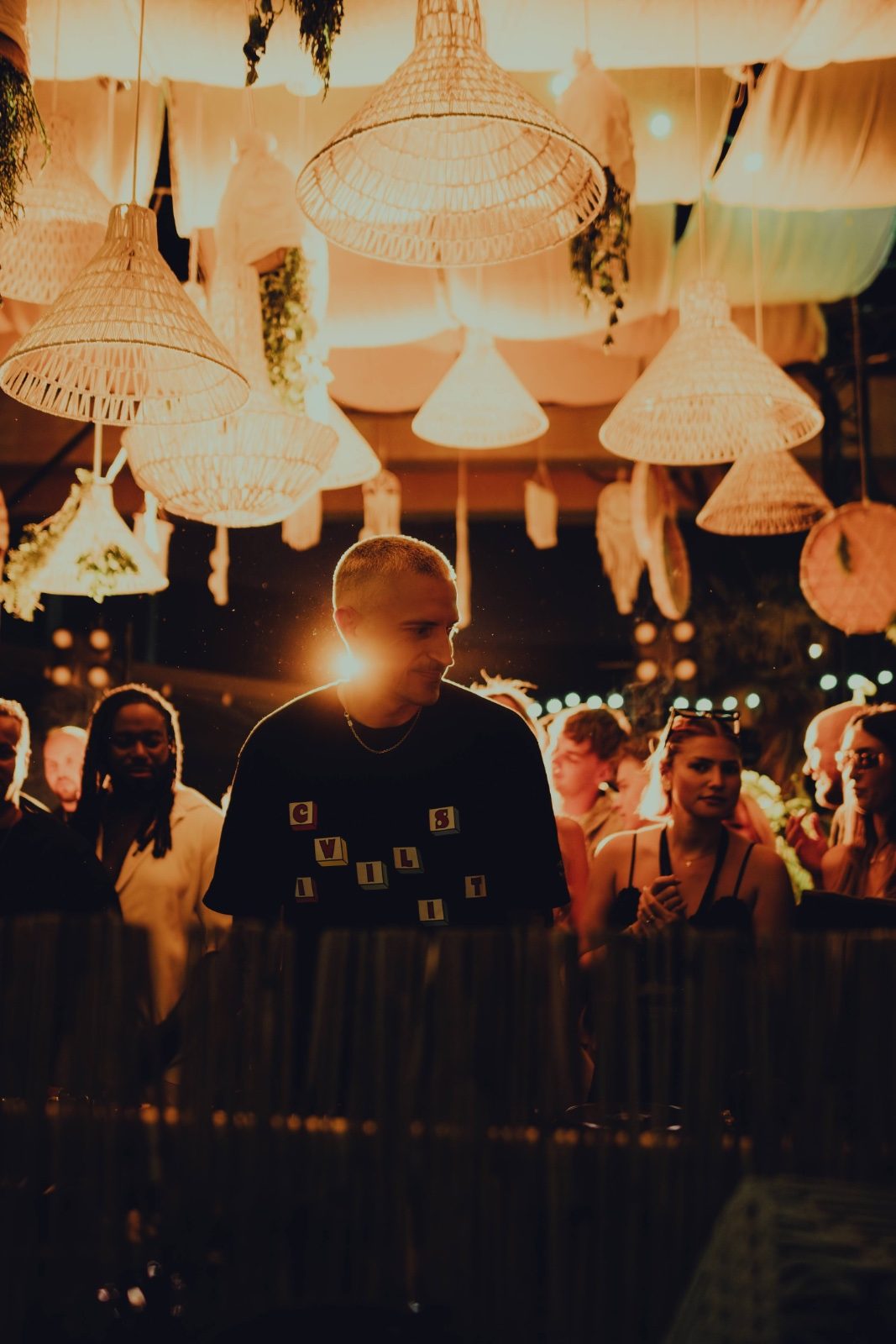 Reznik playing under the woven lamps at an open-air party